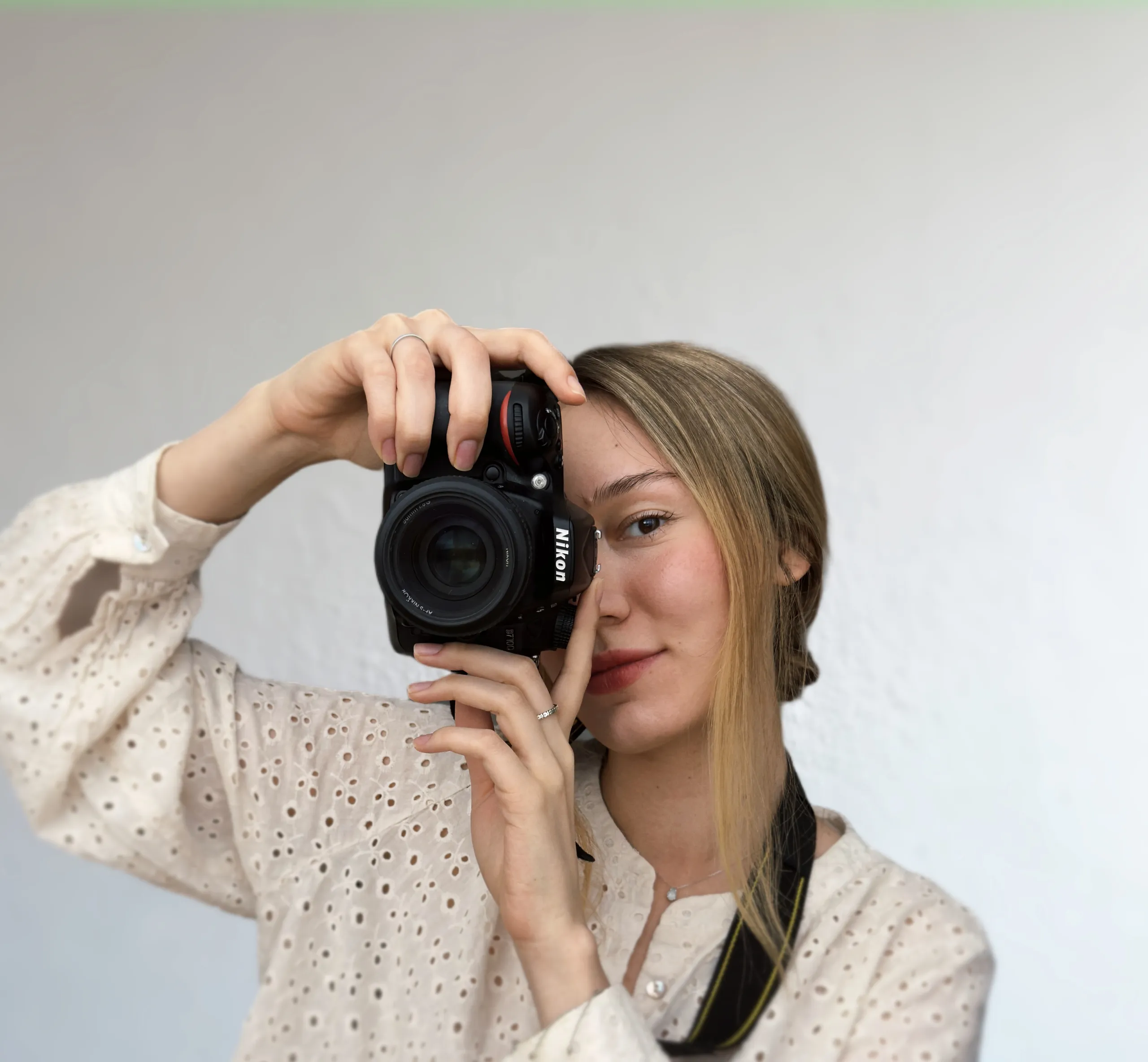 Portrait of a young woman holding a Nikon DSLR camera, showcasing a professional photographer's style in Vienna.